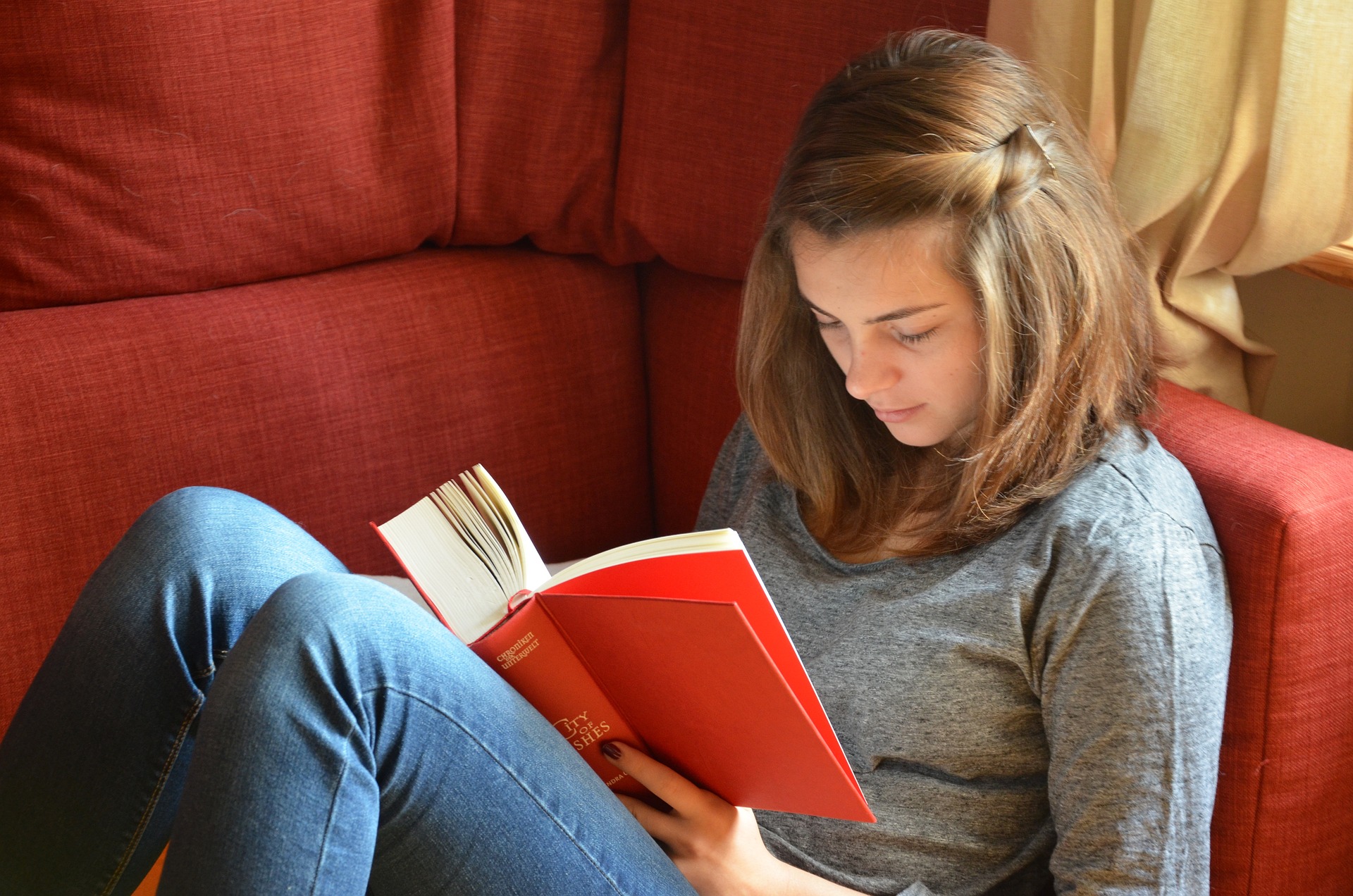 Teen girl sitting on sofa reading